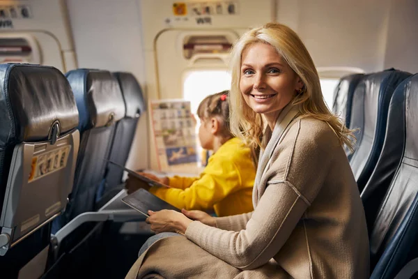 Улыбающаяся женщина в самолете с планшетом — стоковое фото