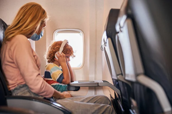 Niño escuchando música a través de auriculares a bordo — Foto de Stock