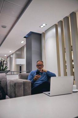 Erkek, cep telefonundan mesaj okuyor.