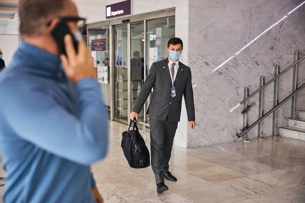 Zakenman met telefoon op zoek naar de luchthavenmedewerker — Stockfoto