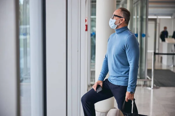 Hombre con máscara facial de pie en la terminal del aeropuerto —  Fotos de Stock