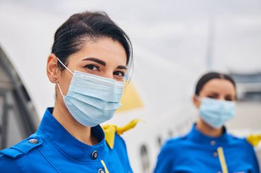 Üniforma giymiş iki hostes dışarıda bekliyor.