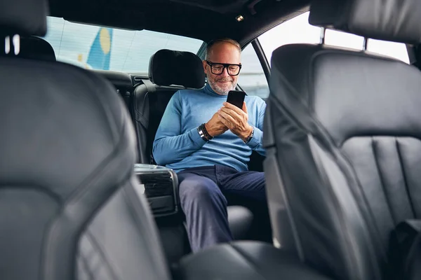 Pasajero con un teléfono móvil sentado en el coche — Foto de Stock