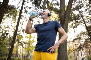 Açık havada çalıştıktan sonra susuzluğunu gideren neşeli bir adam.