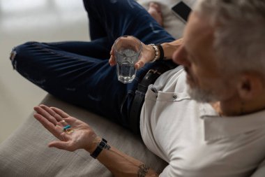 Bir bardak su içen erkek ilacını alıyor.