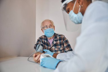 Konsantre doktor, hastanın tansiyonunu ölçüyor.