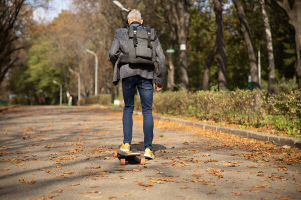 Stylish man going skateboarding in sunny park