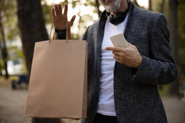 Elegant man walking in park after shopping — Stock Photo, Image