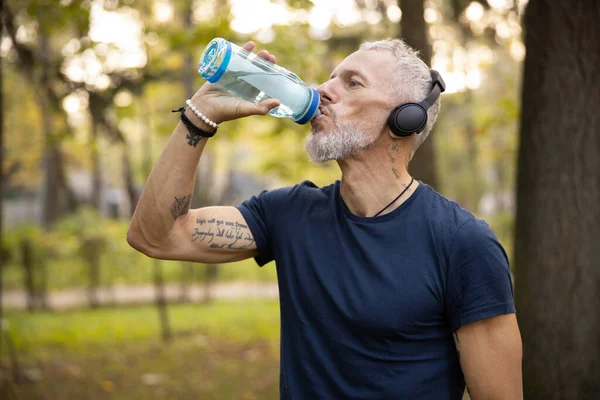 Спортивный человек питьевой воды во время тренировки на открытом воздухе — стоковое фото