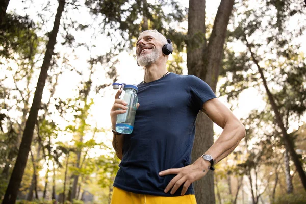 Merry athletic man going jogging in forest