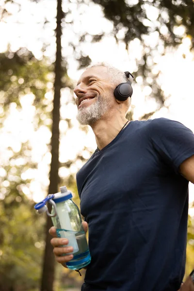 Hombre feliz en forma disfrutando del entrenamiento en el bosque soleado — Foto de Stock