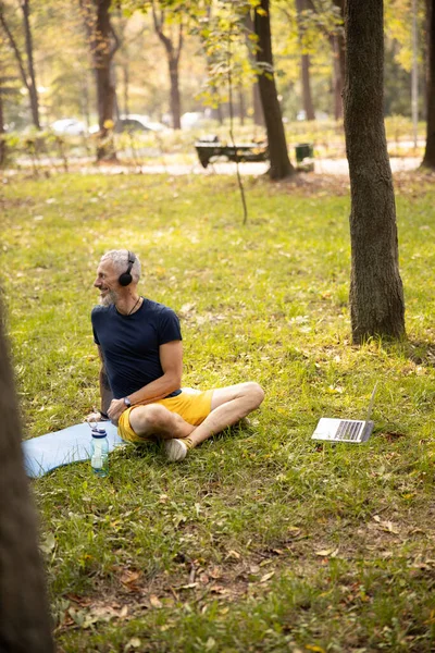 공원에서 인터넷으로 요가하는 행복 한 성인 남자 — 스톡 사진