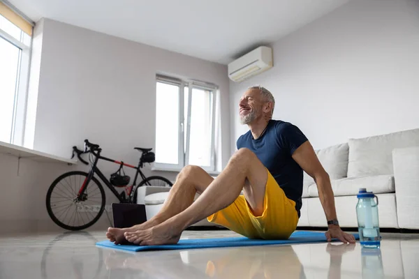 Satisfied athletic male on a rug leaning on his hands