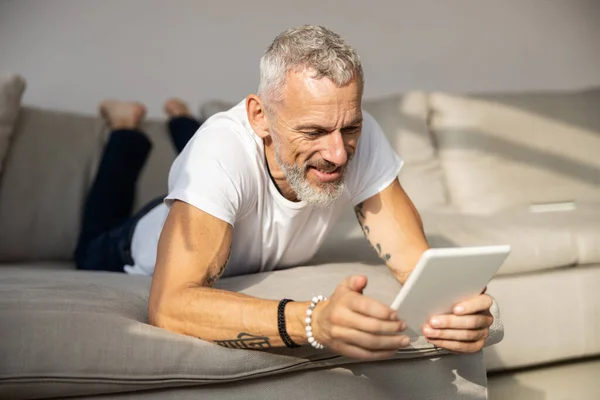 Bărbat odihnindu-se pe burtă cu o tabletă albă — Fotografie, imagine de stoc