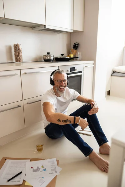Задоволений підприємець зі смартфоном, що сидить на кухні — стокове фото