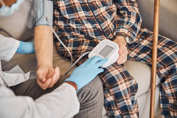 Profesional sanitario que mide la presión arterial del paciente — Foto de Stock