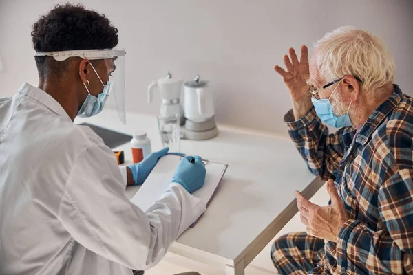 Geriatra describiendo la condición del hombre mayor durante el examen médico — Foto de Stock