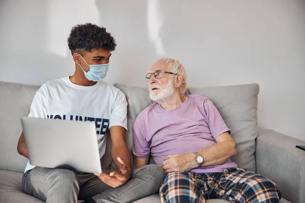 Anciano mirando al voluntario alegre — Foto de Stock