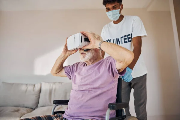 Pensionista masculino en gafas VR sentado en la silla de ruedas — Foto de Stock