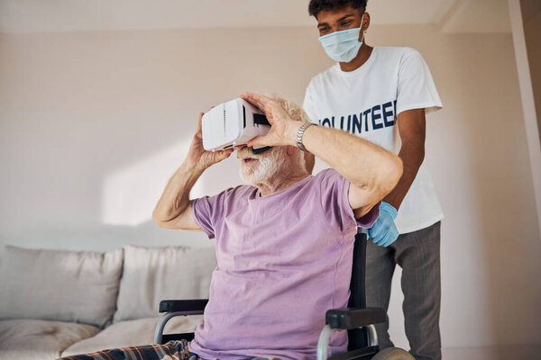 Male pensioner in VR goggles sitting in the wheelchair