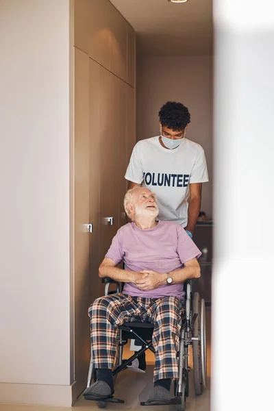 Voluntario en una mascarilla mirando a la persona discapacitada — Foto de Stock