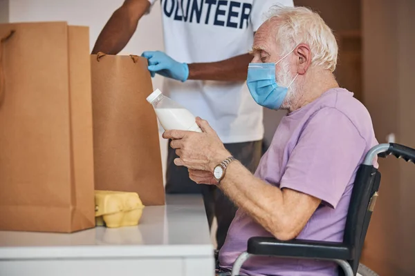 Voluntario en guantes de látex sacando alimentos de la bolsa de papel — Foto de Stock