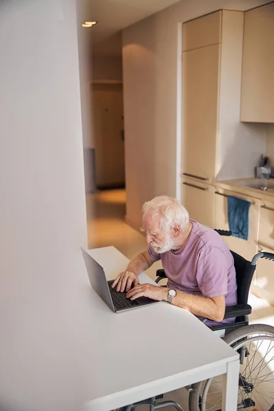 Hombre discapacitado en la silla de ruedas trabajando en su computadora — Foto de Stock