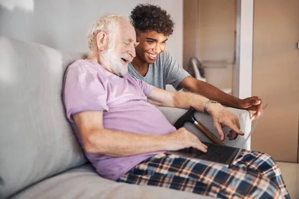 Důchodce a jeho ošetřovatel se dívají na počítač — Stock fotografie