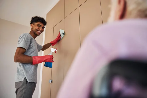 Young man helping a pensioner clean the apartment — Stock Photo, Image