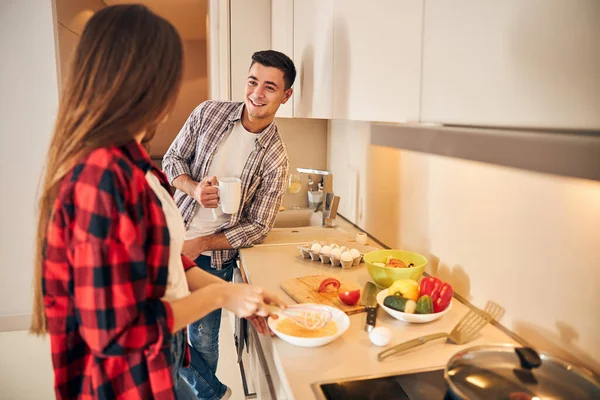 Mężczyzna patrzy na swoją małżonkę gotującą śniadanie — Zdjęcie stockowe