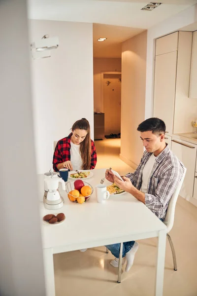 Elinde aleti olan bir adam ve karısı kahvaltı yapıyor. — Stok fotoğraf