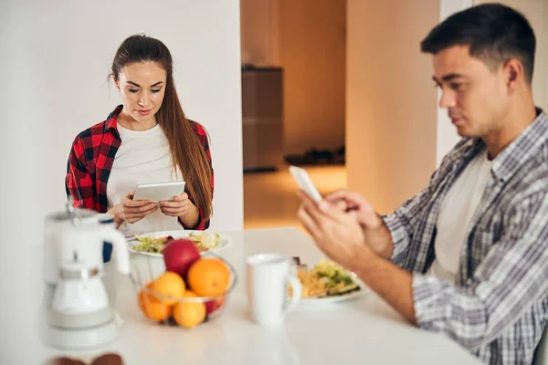 Pareja joven navegando por la web en sus gadgets —  Fotos de Stock