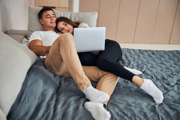Jovens cônjuges assistindo a um programa de TV no laptop — Fotografia de Stock