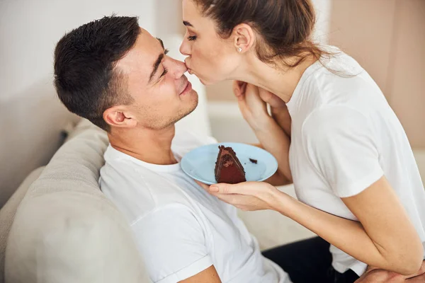 Aimer femme tenant plaque avec gâteau et embrasser son homme — Photo