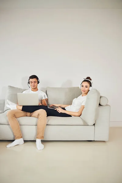 Piękna para pracuje razem z domu siedząc na kanapie — Zdjęcie stockowe