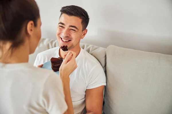 Smiley brünette mann being fed mit schokoladenkuchen — Stockfoto