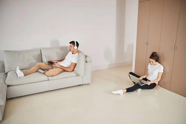 Hårt arbetande par som använder bärbara datorer för att arbeta hemifrån — Stockfoto