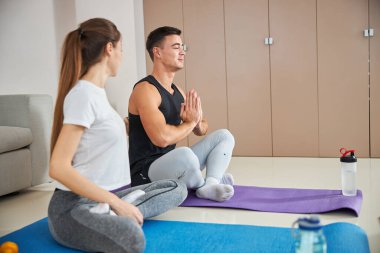 Güzel bayan ve erkek arkadaşı evde yoga yapıyorlar.