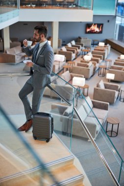 İş adamı ağzına bir bardak getiriyor.