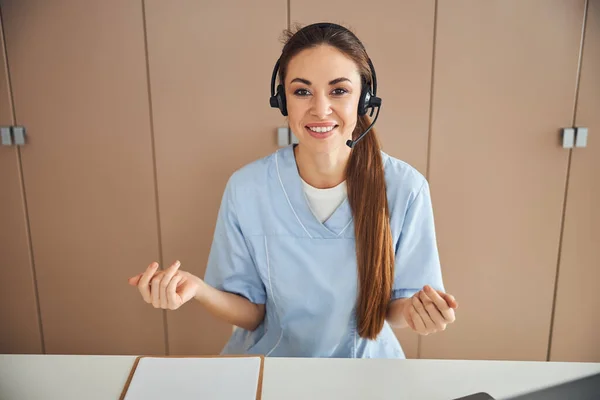 Schöne Ärztin im Headset macht Handgesten — Stockfoto