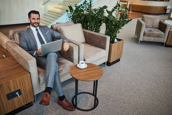 Cheerful adult wearing a business suit relaxing in a lounge — Stock Photo, Image