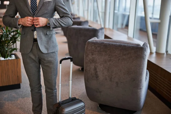 Erkek, tüvit ceketini ilikliyor.