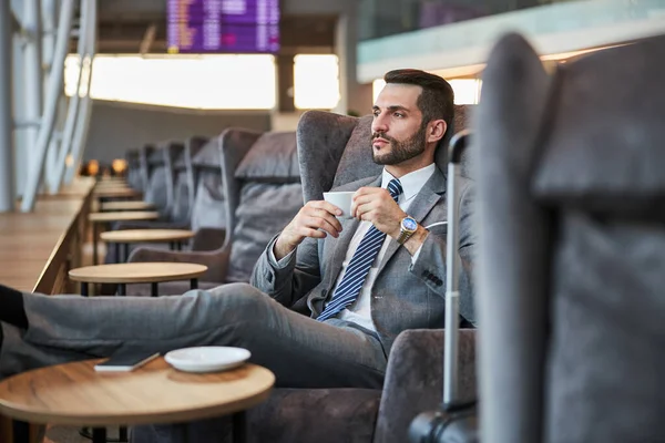 Melancholischer Wirtschaftsbeamter trinkt Espresso mit ausgestreckten Beinen — Stockfoto