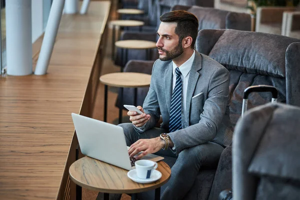 Zakelijk professional nemen van een smartphone tijdens het gebruik van een laptop — Stockfoto