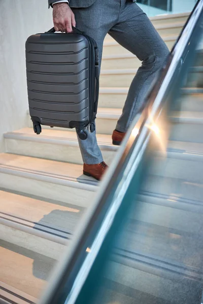 Person hält seinen Koffer in der Nähe des Treppengeländers — Stockfoto