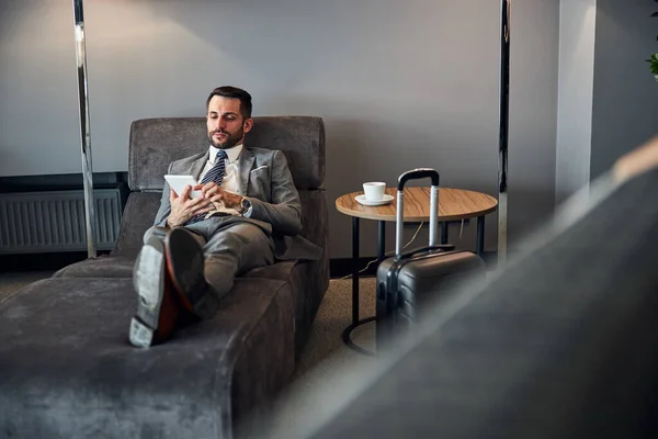 Empreendedor descansando rolando através de seu tablet branco — Fotografia de Stock