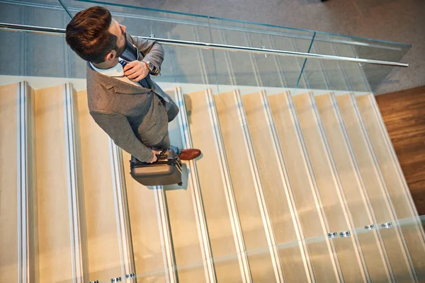 Traveler straightening his tie while descending the stairs — Stock Photo, Image
