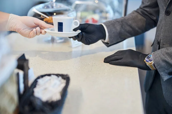 Cafeteria-Mitarbeiterin reicht einem Käufer eine Kaffeetasse — Stockfoto