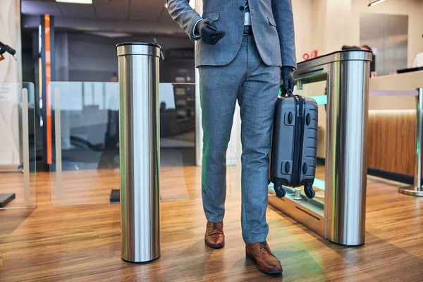 Mann betritt offenes Drehkreuz, während er einen Koffer trägt — Stockfoto