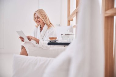 Koltuktaki tablet bilgisayarını kullanan bir spa istemcisi